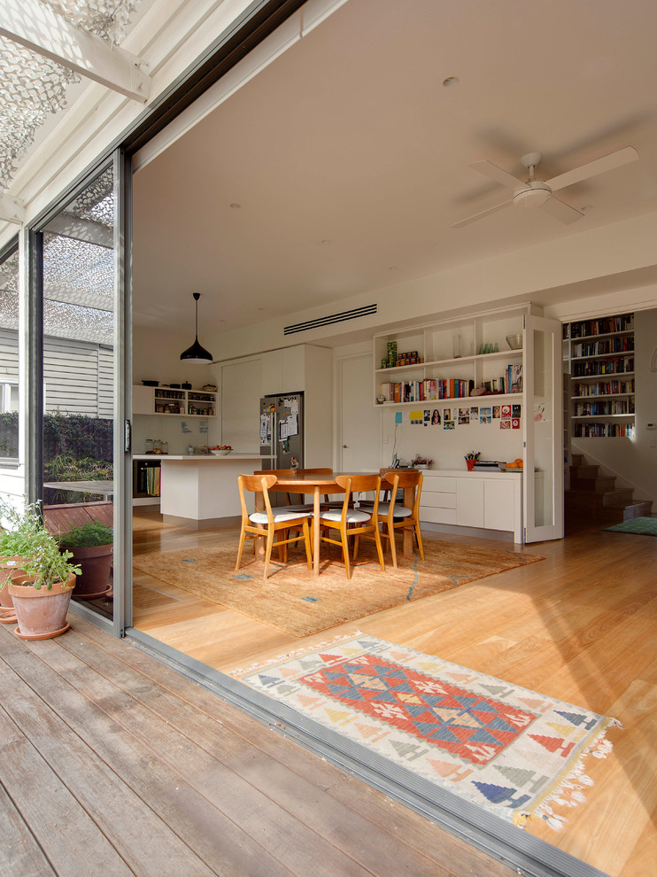 Inspiration for a mid-sized contemporary kitchen/dining combo in Melbourne with white walls, light hardwood floors, a standard fireplace and a metal fireplace surround.