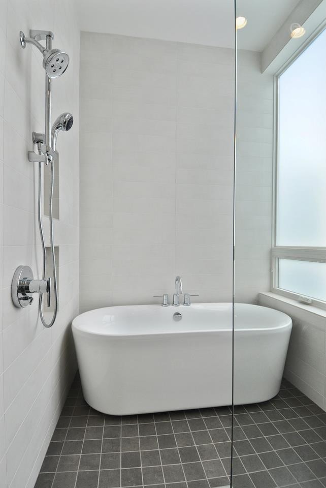This is an example of a mid-sized modern master bathroom in Seattle with a freestanding tub, an open shower, gray tile, stone tile, white walls and porcelain floors.