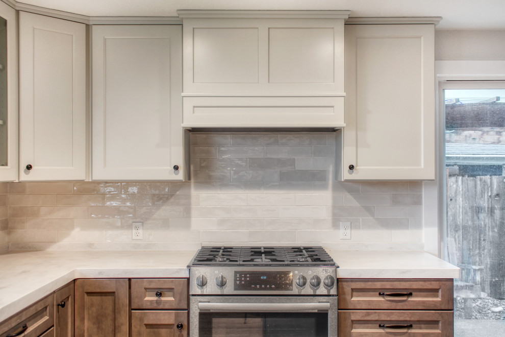 Example of a mid-sized transitional u-shaped light wood floor and brown floor eat-in kitchen design with an undermount sink, recessed-panel cabinets, medium tone wood cabinets, solid surface countertops, white backsplash, ceramic backsplash, stainless steel appliances, an island and white countertops