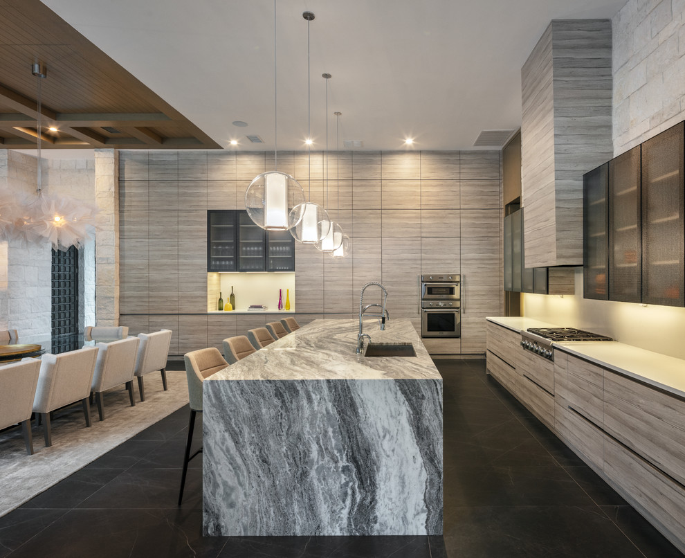 This is an example of a contemporary eat-in kitchen in Austin with flat-panel cabinets, with island, an undermount sink, white splashback, stainless steel appliances, black floor, white benchtop and light wood cabinets.