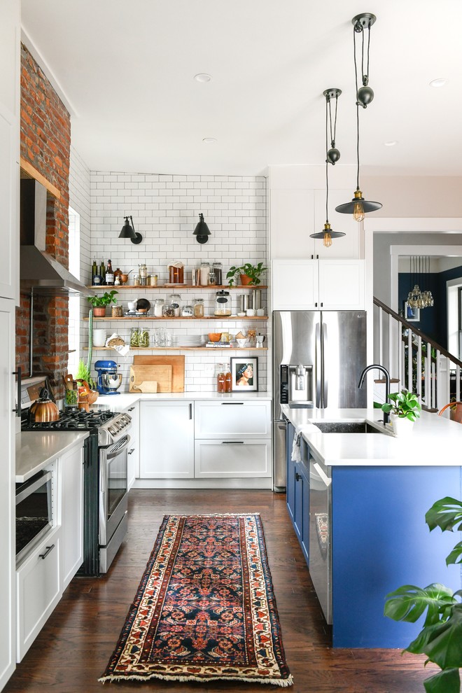 Inspiration for a mid-sized transitional l-shaped eat-in kitchen in Other with an undermount sink, shaker cabinets, blue cabinets, quartz benchtops, white splashback, subway tile splashback, stainless steel appliances, dark hardwood floors, with island, brown floor and white benchtop.