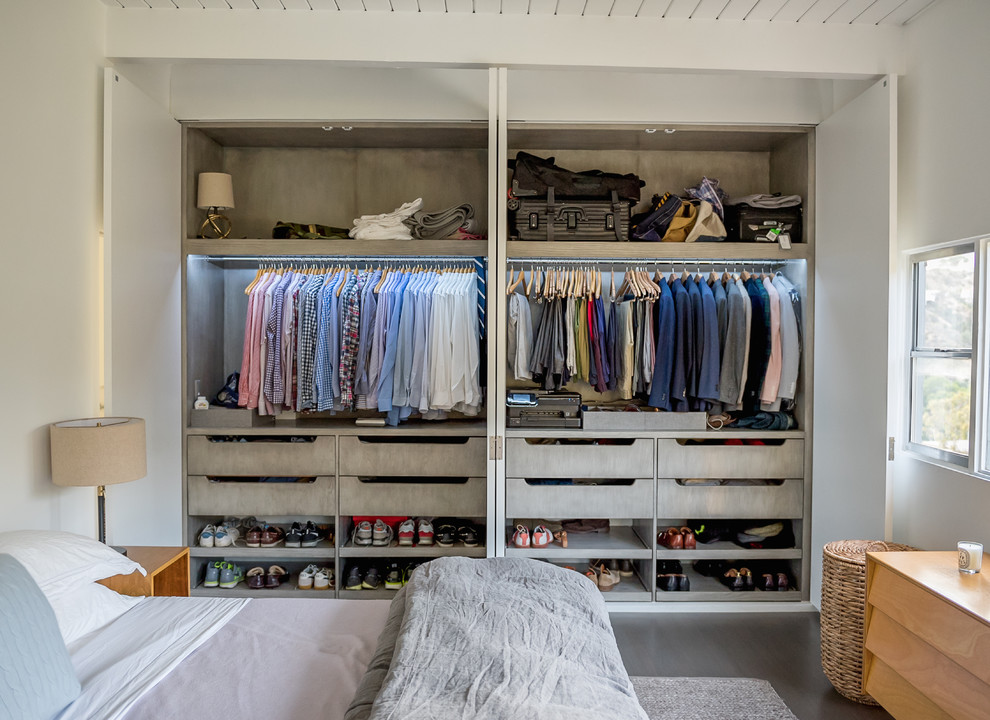Inspiration for a mid-sized modern gender-neutral built-in wardrobe in Los Angeles with flat-panel cabinets, dark hardwood floors, brown floor and grey cabinets.