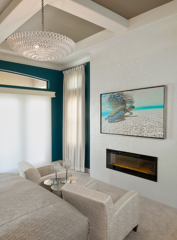 Photo of a large beach style master bedroom in Miami with blue walls, ceramic floors, a standard fireplace, a tile fireplace surround and grey floor.