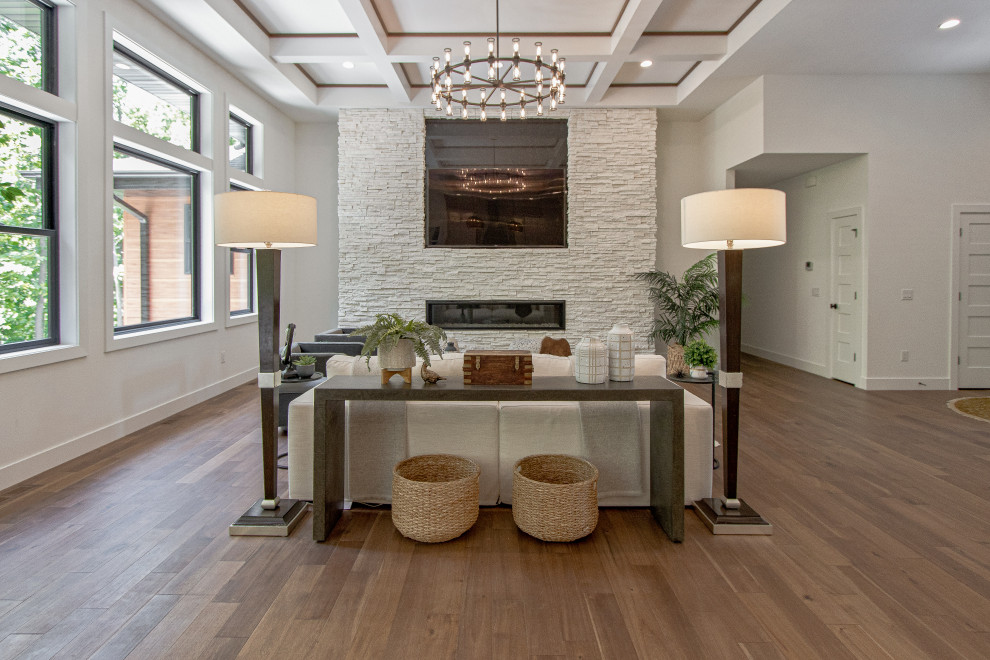 Photo of a transitional formal open concept living room in Other with white walls, medium hardwood floors, a ribbon fireplace, a wall-mounted tv, brown floor and coffered.