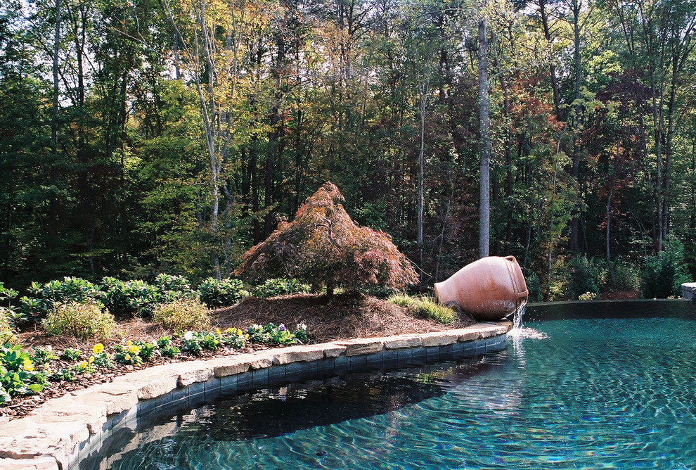 Inspiration for a mid-sized backyard concrete paver and custom-shaped infinity pool fountain remodel