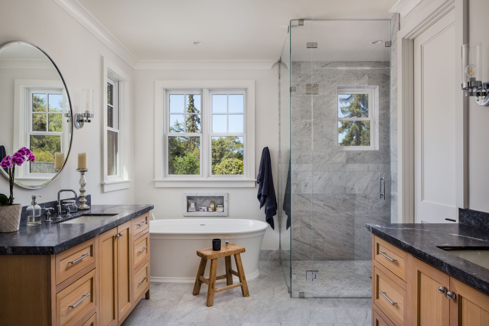 Inspiration for a large transitional master white tile and marble tile marble floor, white floor and double-sink bathroom remodel in San Francisco with shaker cabinets, light wood cabinets, a one-piece toilet, white walls, an undermount sink, marble countertops, a hinged shower door, black countertops, a niche and a built-in vanity