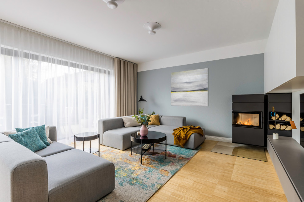 Design ideas for a large scandinavian open concept family room in Dusseldorf with a music area, grey walls, bamboo floors, a hanging fireplace, a metal fireplace surround, a wall-mounted tv, brown floor, wallpaper and wallpaper.
