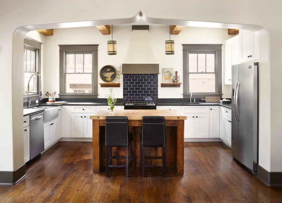 Inspiration for a mid-sized mediterranean u-shaped kitchen in Nashville with white cabinets, blue splashback, subway tile splashback, stainless steel appliances, with island, brown floor, a farmhouse sink, shaker cabinets, wood benchtops and dark hardwood floors.