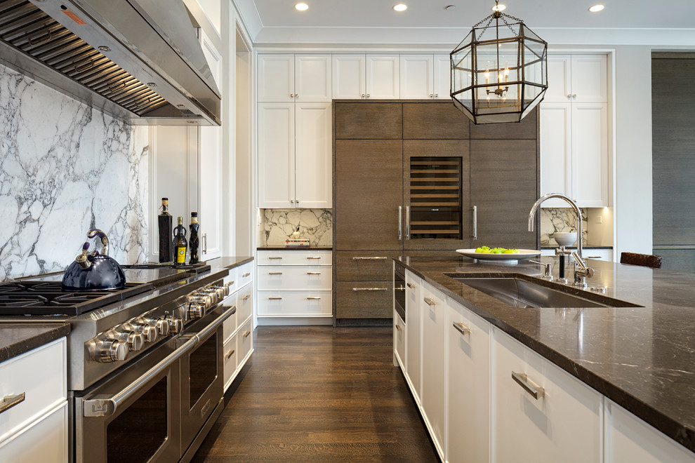 Inspiration for a large transitional l-shaped dark wood floor and brown floor open concept kitchen remodel in Chicago with a farmhouse sink, recessed-panel cabinets, white cabinets, marble countertops, multicolored backsplash, marble backsplash, stainless steel appliances and an island