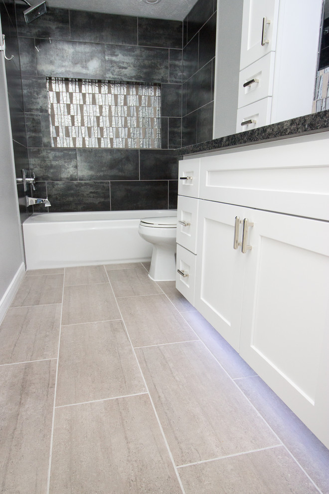Design ideas for a small modern 3/4 bathroom in Houston with shaker cabinets, white cabinets, an alcove tub, a shower/bathtub combo, porcelain floors, an undermount sink, granite benchtops, a two-piece toilet, multi-coloured tile, porcelain tile, black walls and grey floor.