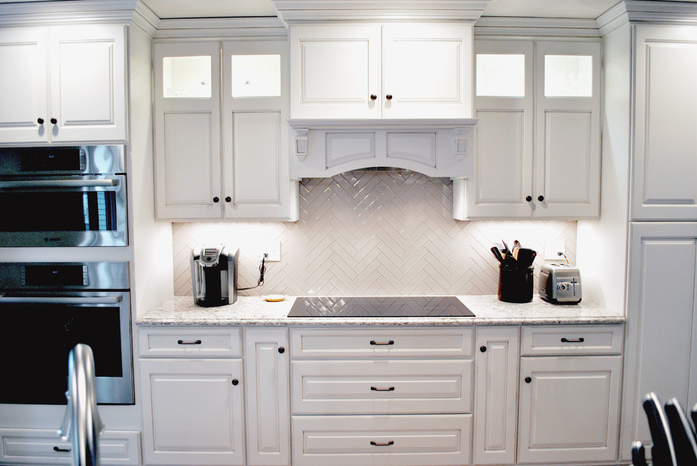 Open concept kitchen - transitional l-shaped medium tone wood floor open concept kitchen idea in St Louis with raised-panel cabinets, white cabinets, granite countertops, white backsplash, ceramic backsplash, stainless steel appliances and an island