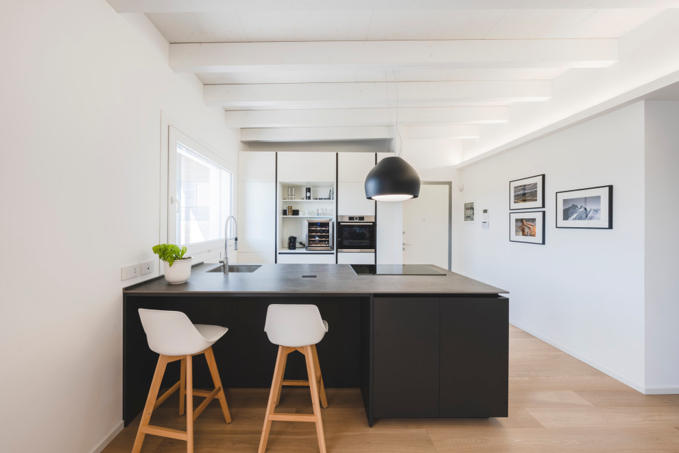 Mid-sized danish galley beige floor, wood ceiling and light wood floor open concept kitchen photo in Milan with an undermount sink, flat-panel cabinets, white cabinets, solid surface countertops, stainless steel appliances, an island and gray countertops