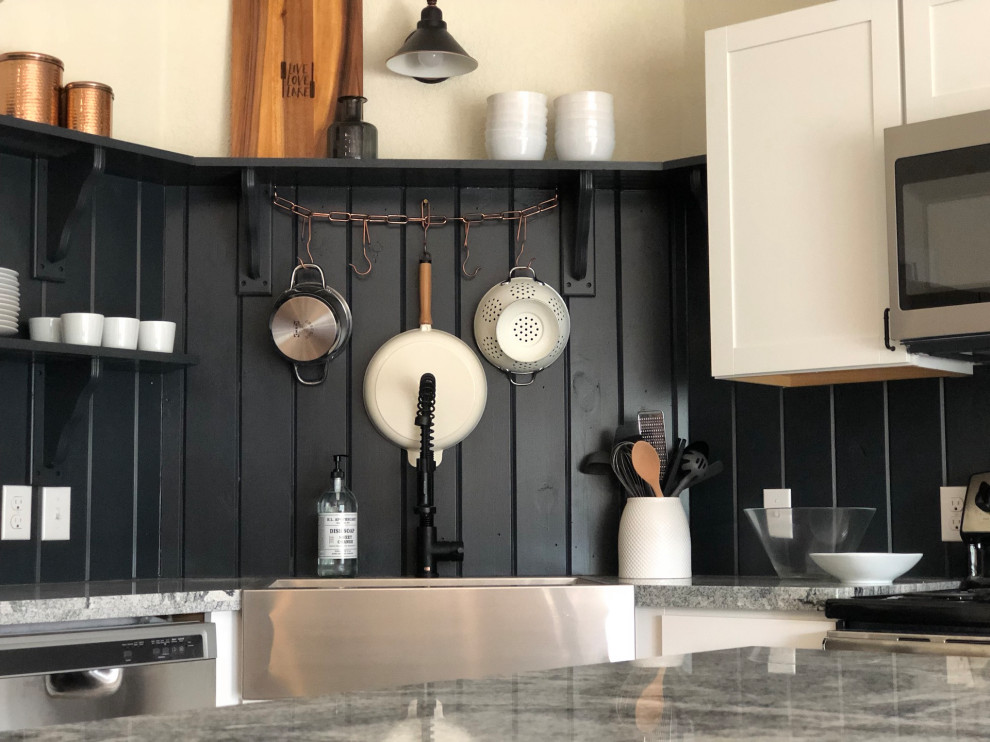 Foto på ett grå kök, med en rustik diskho, skåp i shakerstil, vita skåp, svart stänkskydd, stänkskydd i trä, rostfria vitvaror och en köksö