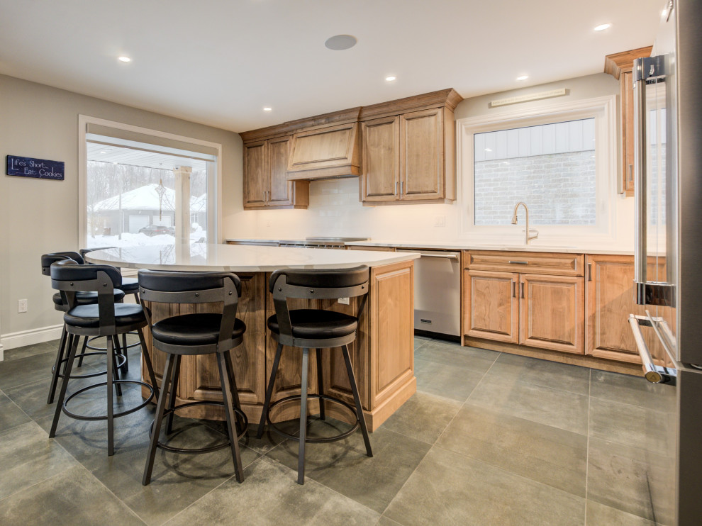 Mid-sized transitional l-shaped eat-in kitchen photo in Toronto with an undermount sink, raised-panel cabinets, medium tone wood cabinets, quartz countertops, white backsplash, ceramic backsplash, stainless steel appliances, an island and white countertops