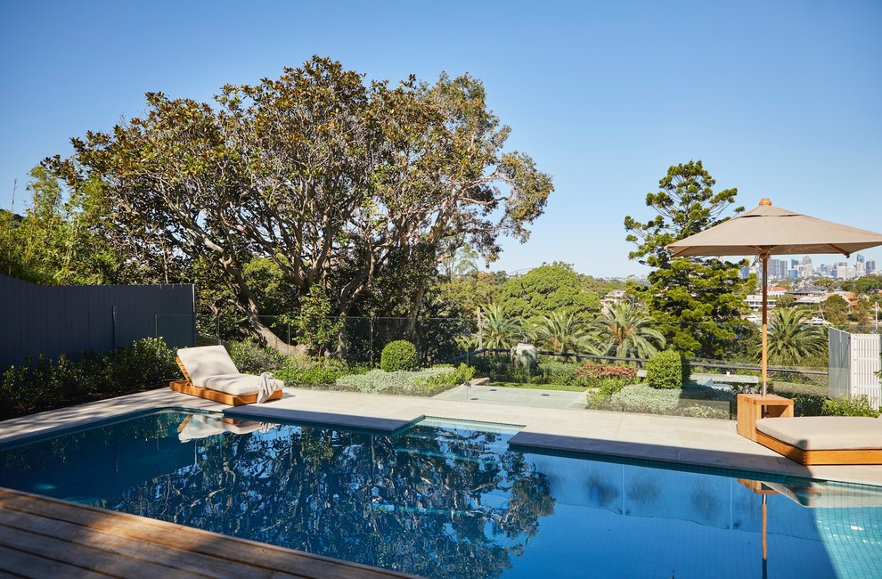 Photo of a large contemporary backyard rectangular pool in Sydney with natural stone pavers.