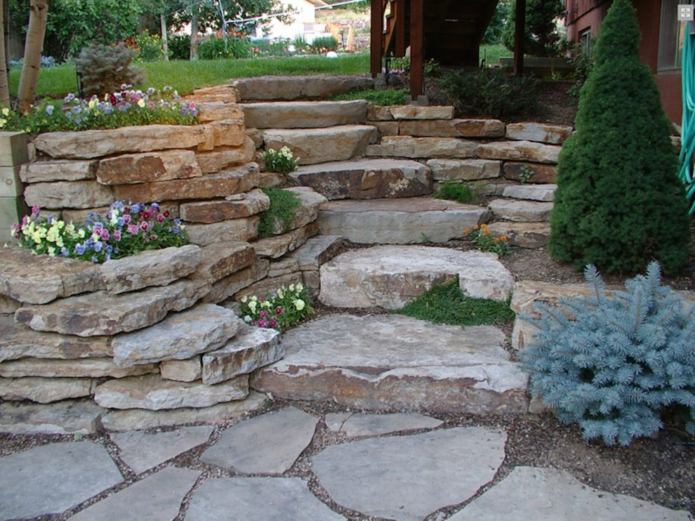 Inspiration for a small backyard partial sun garden in Denver with a retaining wall and natural stone pavers.