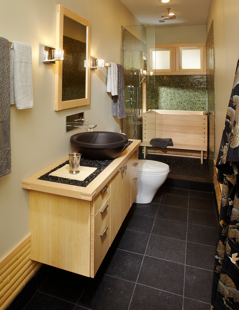 Photo of a mid-sized asian master bathroom in Chicago with flat-panel cabinets, light wood cabinets, an alcove shower, a vessel sink, wood benchtops, beige walls, a one-piece toilet and slate floors.