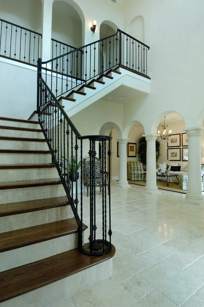 Inspiration for a mediterranean wood l-shaped staircase in Tampa with travertine risers and metal railing.