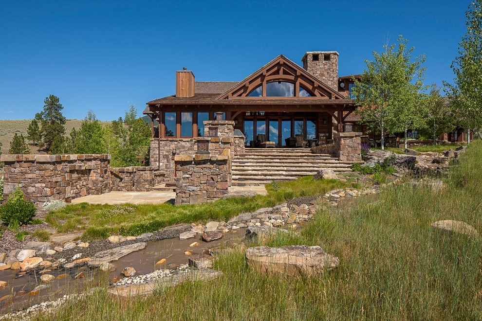 Photo of a large rustic full sun backyard stone landscaping.