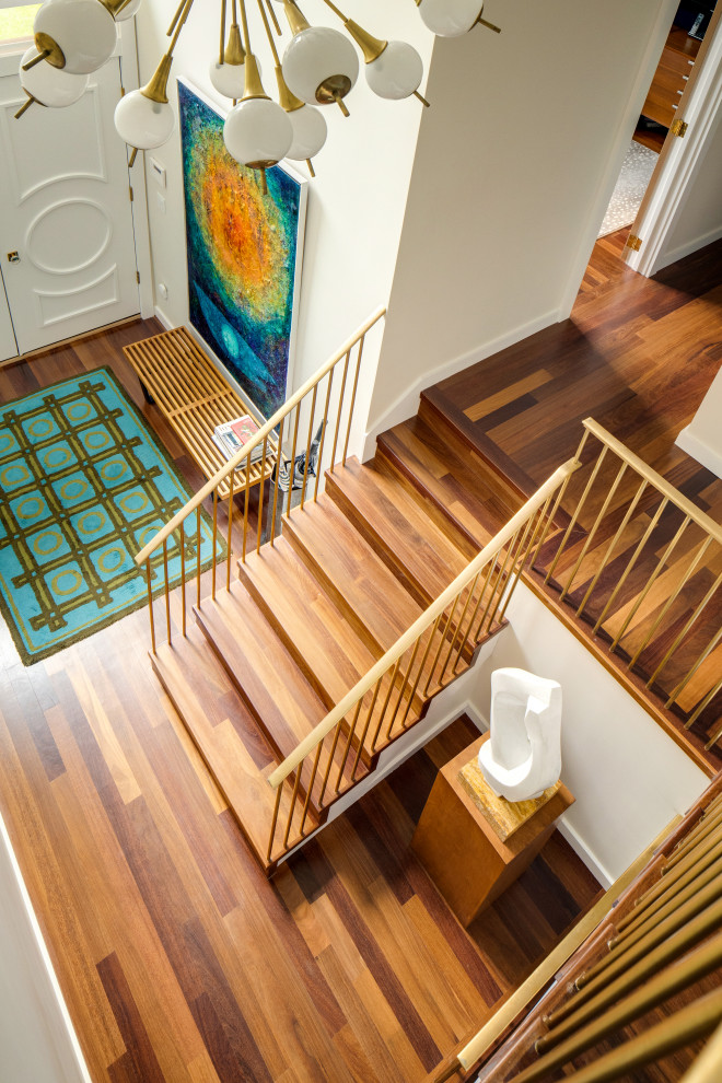 This is an example of an expansive midcentury wood u-shaped metal railing staircase in New York with wood risers.