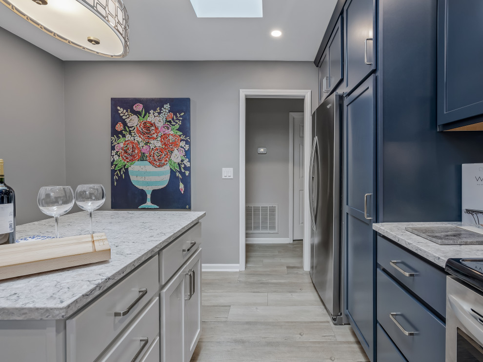 Example of a large transitional l-shaped kitchen design in Raleigh with an undermount sink, recessed-panel cabinets, quartz countertops, porcelain backsplash, stainless steel appliances and an island