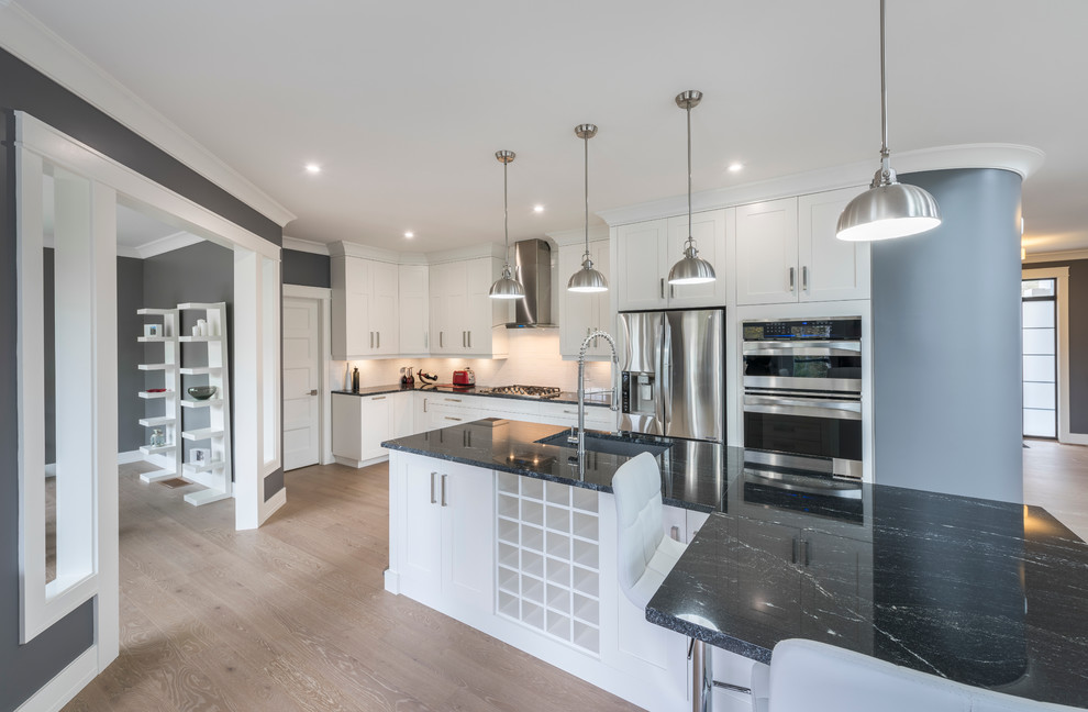 Inspiration for a transitional light wood floor kitchen remodel with an undermount sink, recessed-panel cabinets, white cabinets, white backsplash and an island