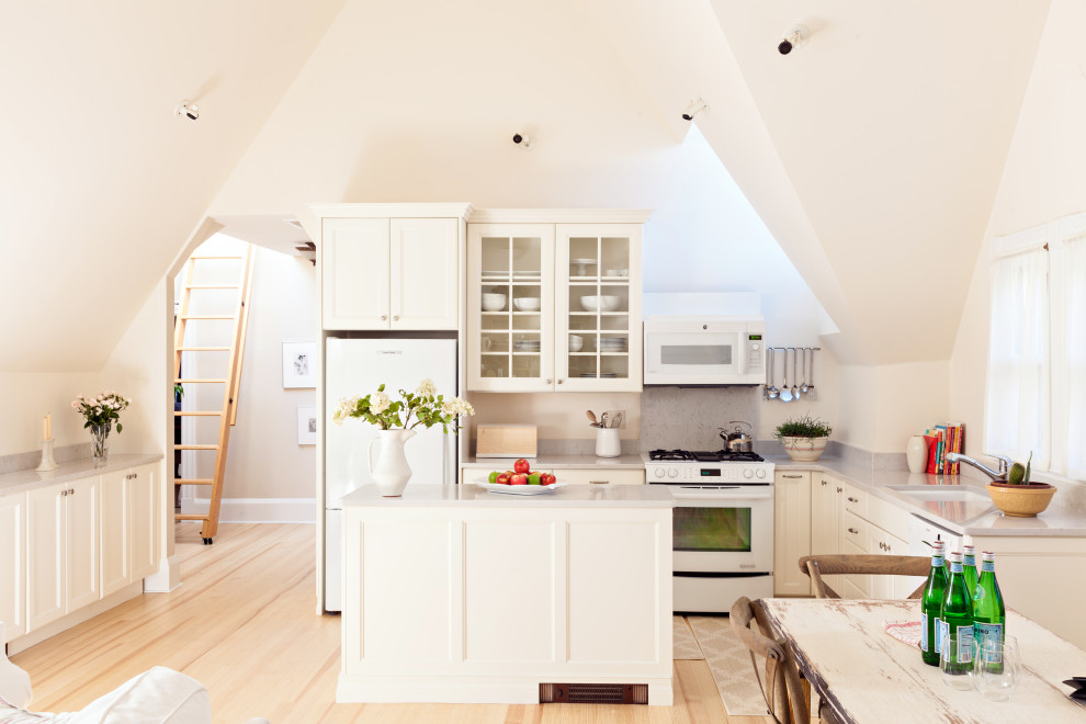 Inspiration for a transitional l-shaped light wood floor, beige floor and vaulted ceiling kitchen remodel in Boston with an undermount sink, recessed-panel cabinets, white cabinets, white appliances, an island and gray countertops
