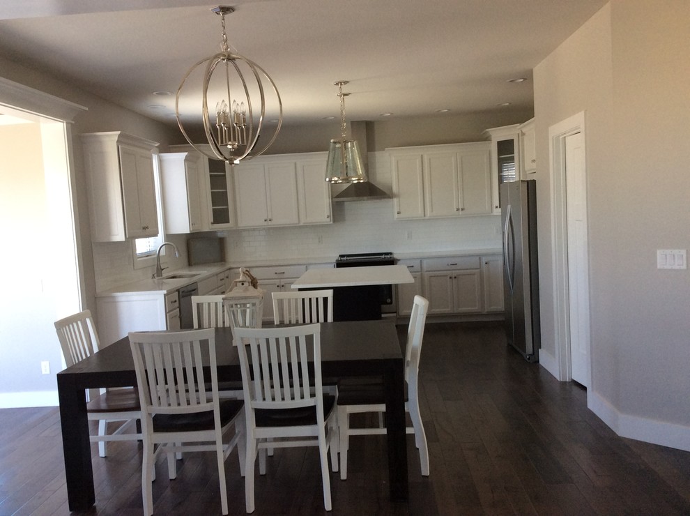 Example of a mid-sized transitional u-shaped dark wood floor eat-in kitchen design in Chicago with an undermount sink, shaker cabinets, white cabinets, quartz countertops, white backsplash, subway tile backsplash, stainless steel appliances and an island