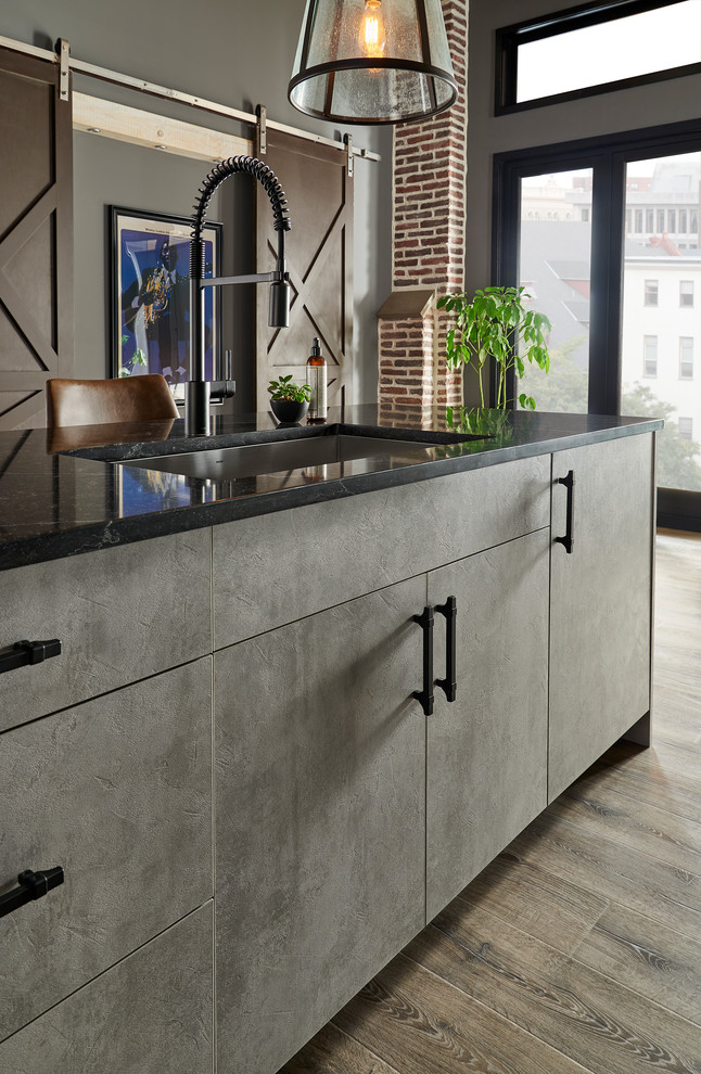 Mid-sized modern single-wall eat-in kitchen in New York with an undermount sink, flat-panel cabinets, black cabinets, solid surface benchtops, grey splashback, glass sheet splashback, stainless steel appliances, with island, brown floor and black benchtop.