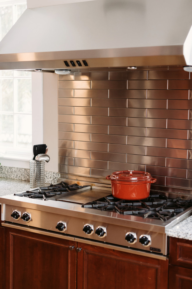 Eat-in kitchen - large transitional u-shaped medium tone wood floor eat-in kitchen idea with recessed-panel cabinets, brown cabinets, granite countertops, metallic backsplash, subway tile backsplash, stainless steel appliances and gray walls