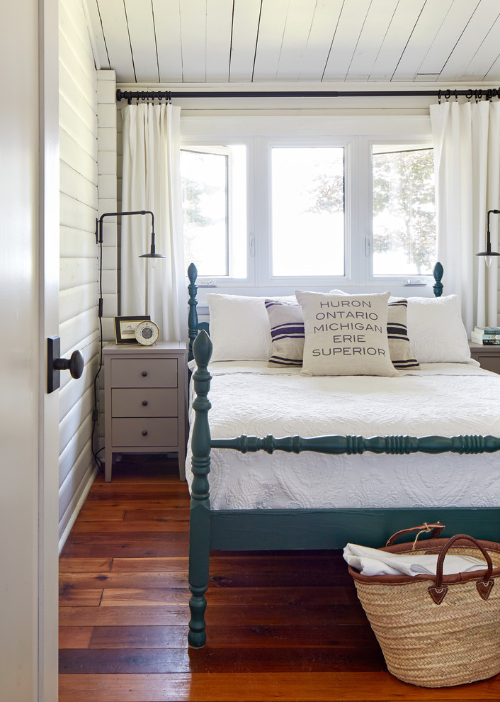 Photo of a mid-sized beach style guest bedroom in Toronto with white walls, medium hardwood floors and brown floor.