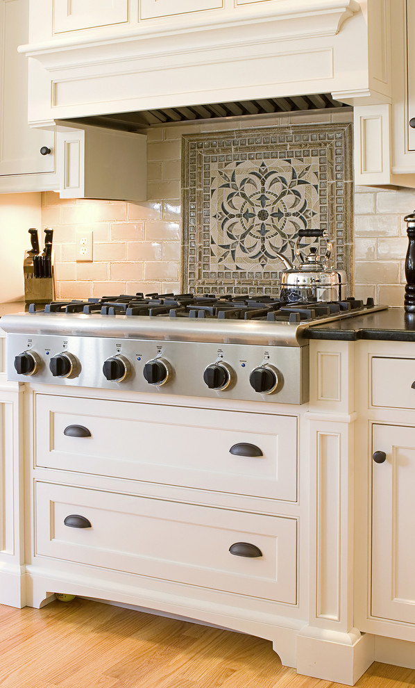 Example of a mid-sized transitional l-shaped eat-in kitchen design in Toronto with flat-panel cabinets, white cabinets, granite countertops, beige backsplash, ceramic backsplash and stainless steel appliances