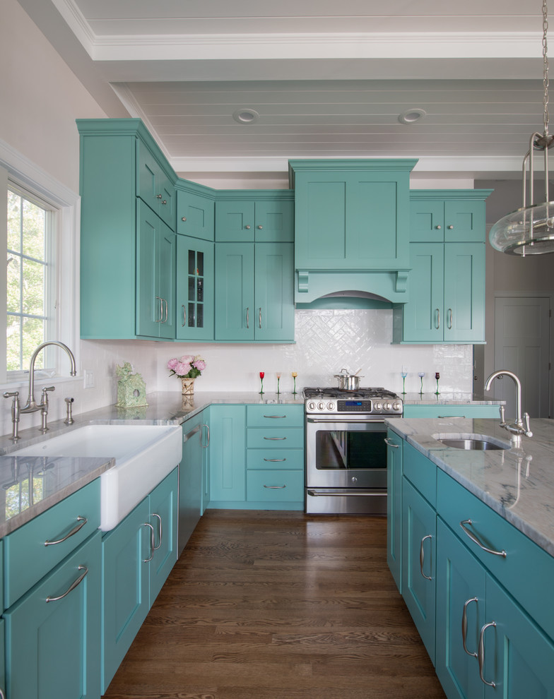 Photo of a transitional l-shaped kitchen in Providence with a farmhouse sink, shaker cabinets, blue cabinets, white splashback, stainless steel appliances, dark hardwood floors, with island and brown floor.