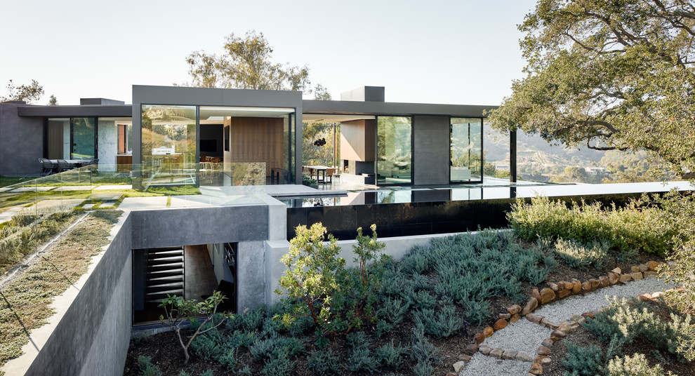 Modern two-storey grey house exterior in Los Angeles with mixed siding, a flat roof and a green roof.