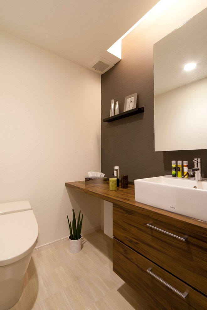 This is an example of a small contemporary powder room in Tokyo with a one-piece toilet, flat-panel cabinets, white walls and a vessel sink.