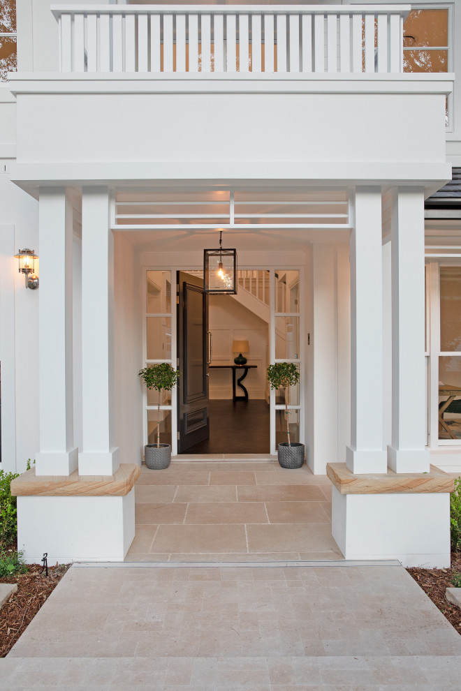 Photo of a large beach style front door in Sydney with white walls, travertine floors, a single front door, a black front door and beige floor.