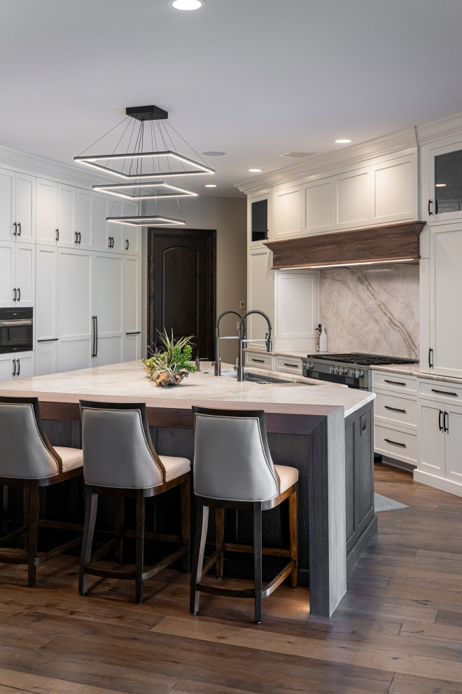 Inspiration for a large transitional medium tone wood floor and brown floor open concept kitchen remodel with a double-bowl sink, flat-panel cabinets, white cabinets, quartzite countertops, beige backsplash, stainless steel appliances, an island and beige countertops