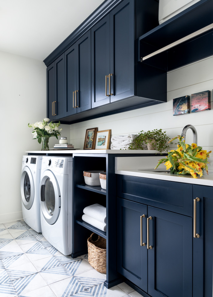 Design ideas for a large transitional galley dedicated laundry room in Nashville with an undermount sink, shaker cabinets, blue cabinets, quartz benchtops, shiplap splashback, white walls, porcelain floors, a side-by-side washer and dryer, multi-coloured floor, white benchtop and planked wall panelling.