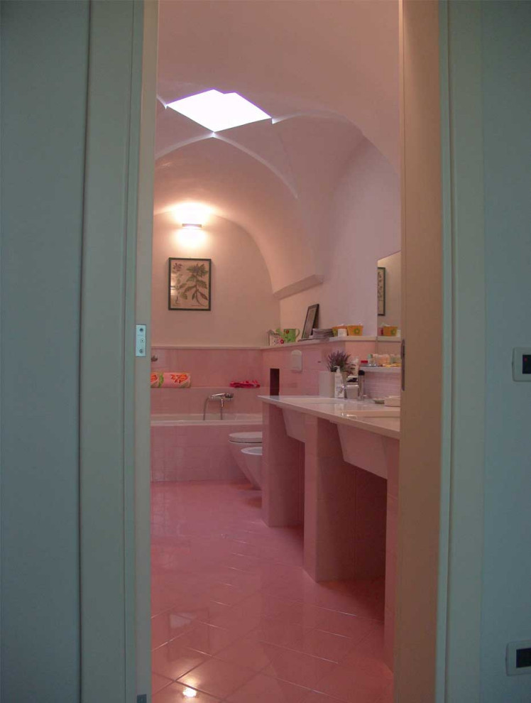 Réalisation d'une salle de bain tradition avec une baignoire en alcôve, un carrelage rose, des carreaux de céramique, un mur blanc, un sol en carrelage de céramique, un lavabo encastré, un plan de toilette en marbre, un sol rose, meuble double vasque, un plafond voûté, une niche et un plan de toilette blanc.