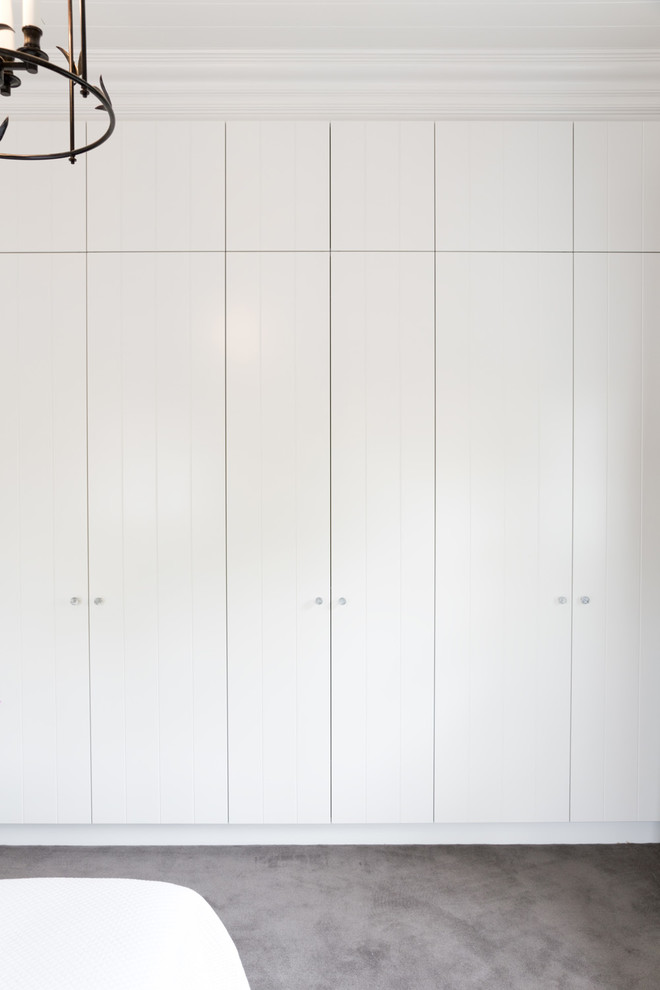 Large traditional gender-neutral walk-in wardrobe in Sydney with white cabinets and carpet.