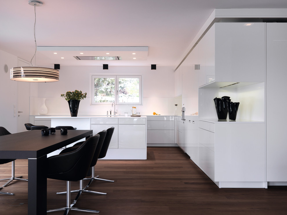 This is an example of a contemporary l-shaped eat-in kitchen in Other with flat-panel cabinets, white cabinets, dark hardwood floors and with island.