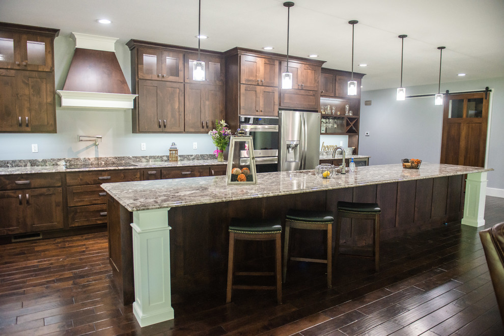 Example of a transitional l-shaped open concept kitchen design with an undermount sink, shaker cabinets, dark wood cabinets, granite countertops, stainless steel appliances, an island and multicolored countertops