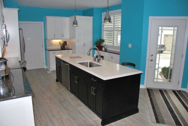 Inspiration for a mid-sized transitional l-shaped porcelain tile and beige floor kitchen remodel in Toronto with an undermount sink, recessed-panel cabinets, white cabinets, granite countertops, white backsplash, subway tile backsplash, stainless steel appliances, an island and black countertops