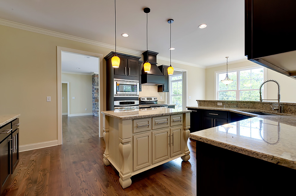 Transitional u-shaped medium tone wood floor eat-in kitchen photo with an undermount sink, recessed-panel cabinets, dark wood cabinets, granite countertops and an island