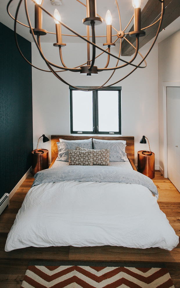 Design ideas for a mid-sized midcentury loft-style bedroom in Calgary with white walls and medium hardwood floors.