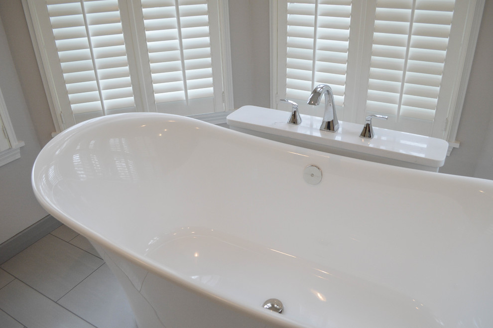 Mid-sized transitional master gray tile and porcelain tile porcelain tile freestanding bathtub photo in Cleveland with recessed-panel cabinets, white cabinets, a two-piece toilet, gray walls, an undermount sink and quartz countertops
