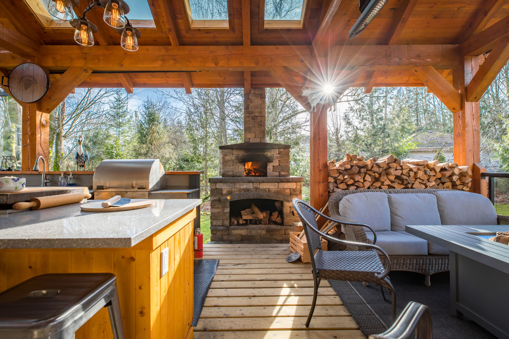 Example of a large mountain style backyard outdoor kitchen deck design in Vancouver with a roof extension