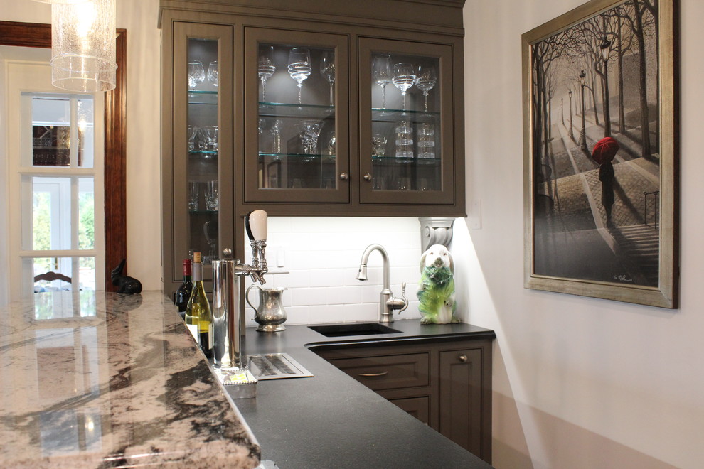 Inspiration for a small transitional l-shaped wet bar in Philadelphia with an undermount sink, glass-front cabinets, grey cabinets, white splashback and light hardwood floors.