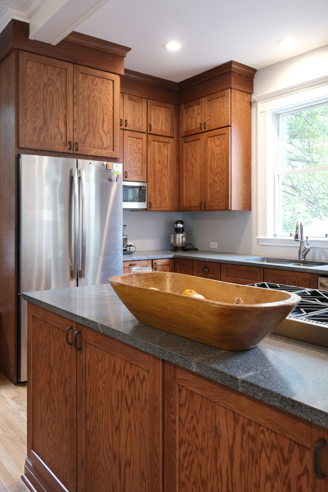 Large traditional l-shaped kitchen/diner in Baltimore with a submerged sink, shaker cabinets, medium wood cabinets, granite worktops, stainless steel appliances, light hardwood flooring, an island, brown floors, grey worktops and exposed beams.
