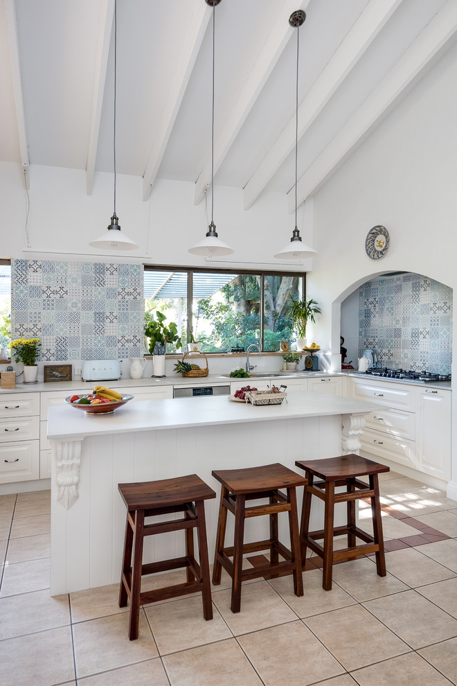 Photo of a mid-sized country l-shaped kitchen in Perth with an undermount sink, shaker cabinets, solid surface benchtops, blue splashback, ceramic splashback, stainless steel appliances, ceramic floors, with island and white benchtop.